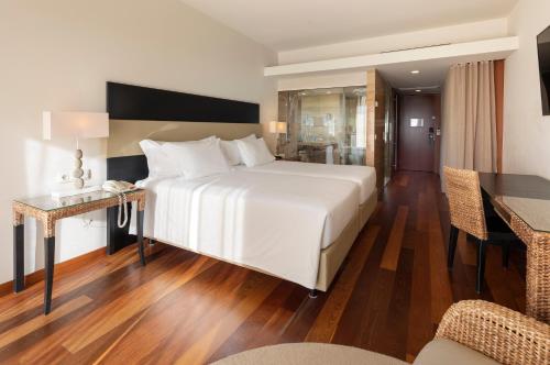 a bedroom with a large white bed and a table at Crowne Plaza Vilamoura - Algarve by IHG in Vilamoura