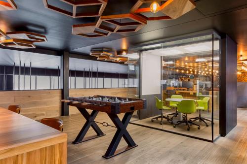 a room with a ping pong table and green chairs at Fiesta Americana Viaducto Aeropuerto in Mexico City