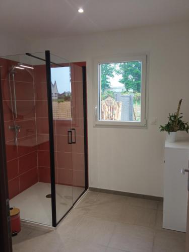 La salle de bains est pourvue d'une douche et d'une fenêtre. dans l'établissement Gîte du bois des Bruyères, à Drancourt