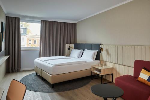 a hotel room with a bed and a red chair at Crowne Plaza Hamburg-City Alster by IHG in Hamburg