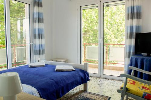 a bedroom with a bed with blue sheets and windows at Maria house in Eleonas