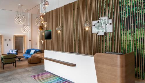 a lobby with a reception desk with a wall at Holiday Inn Munich - Leuchtenbergring by IHG in Munich