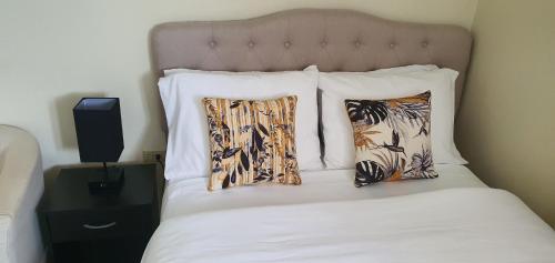 a bed with white sheets and two pillows on it at Hastings Towers 4D - Studio Apt Opp Beach in Bridgetown