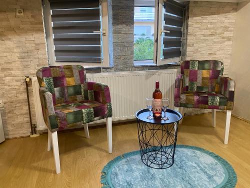 2 sillas y una mesa con una botella de vino en President spa apartman Arandjelovac en Arandjelovac