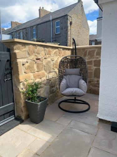 a chair sitting on a patio next to a stone wall at The Anchorage - sea views and beach on doorstep in Amble