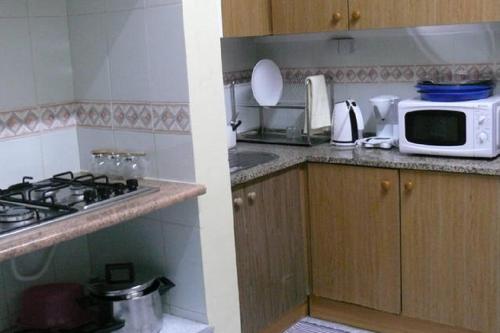a kitchen with a stove, microwave, and dishwasher at Nations Rooms in Lisbon