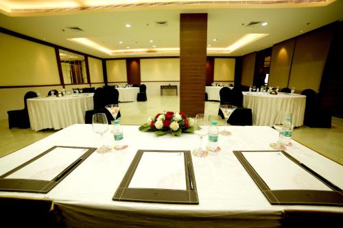 a table with glasses and flowers on it in a room at The Lalit Traveller- Airport hotel in Jaipur