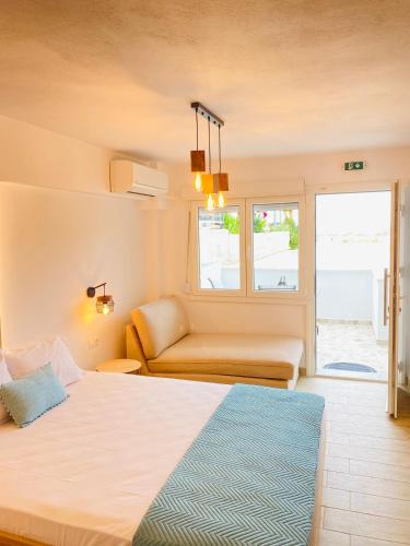 a bedroom with a bed and a couch and a window at Ifigenia Sea View Apartments in Chrysi Ammoudia