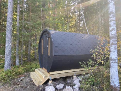 a black hut sitting on a bridge in the woods at IGMA Lodge in Borlänge