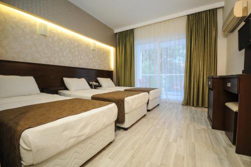 a hotel room with three beds and a window at Palmea Hotel in Marmaris