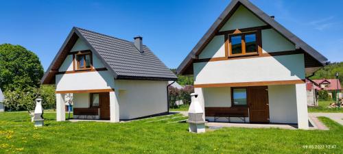 a small house with a black roof at Domki - Noclegi Pod Ostrym Działem in Ustrzyki Dolne