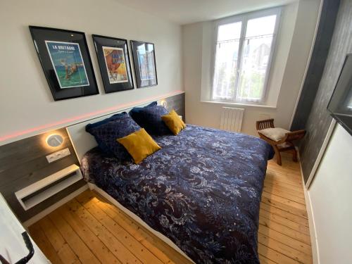 a bedroom with a bed with blue and yellow pillows at Maison bord de mer « Le Bateau IvRe » in Saint Malo