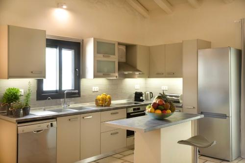 a kitchen with white cabinets and a bowl of fruit on the counter at Casa Serenity in Agios Ioannis