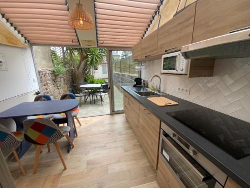 une cuisine avec un évier et une table avec des chaises dans l'établissement Maison bord de mer « Le Bateau IvRe », à Saint-Malo