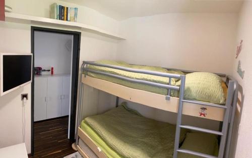 ツェルマットにあるApartment Zayetta Nr. 16の二段ベッド2台、テレビが備わる小さな客室です。