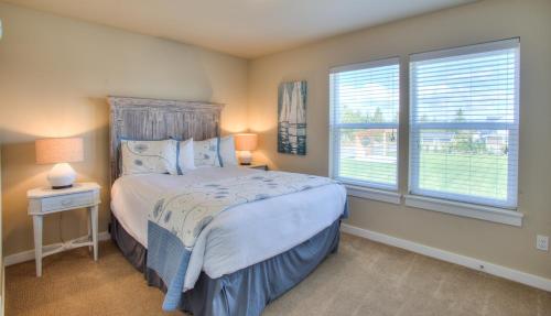 a bedroom with a bed and two windows at Salty Paws - Oyhut Bay Seaside Village in Ocean Shores