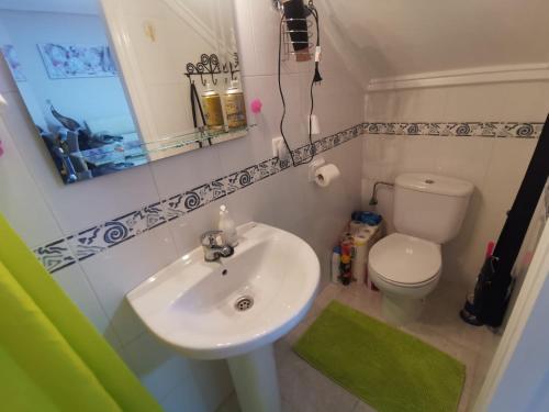 W łazience znajduje się umywalka, toaleta i lustro. w obiekcie Casa Malibu w mieście Ciudad Quesada