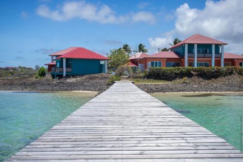 a wooden pathway leading to a house in the water at Les Villas du Lagon in Le François