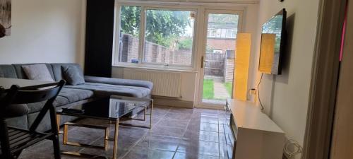 sala de estar con sofá, mesa y ventana en 3 bed bedroom house with garden en Thamesmead