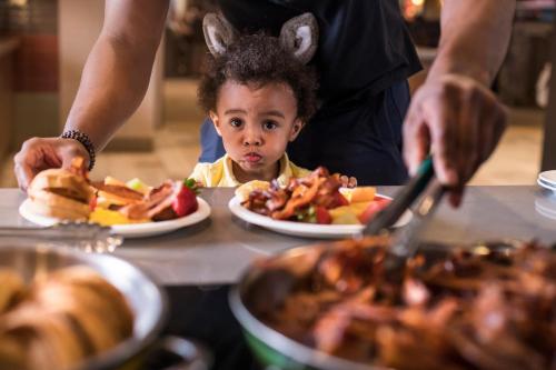 a little boy sitting at a table with plates of food at Great Wolf Lodge Traverse City in Traverse City