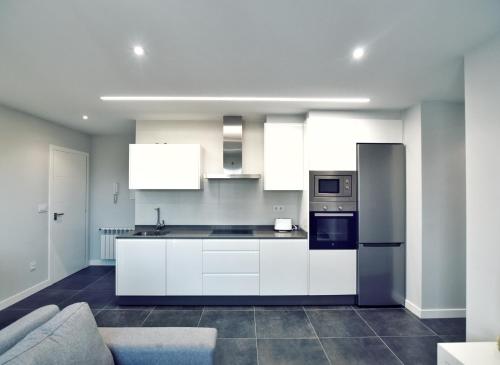 uma cozinha com armários brancos e um frigorífico de aço inoxidável em Apartamento Las Perdices II em Meaño