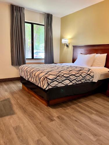 a bedroom with a bed with a wooden headboard and a window at Rodeway Inn Boise Airport in Boise