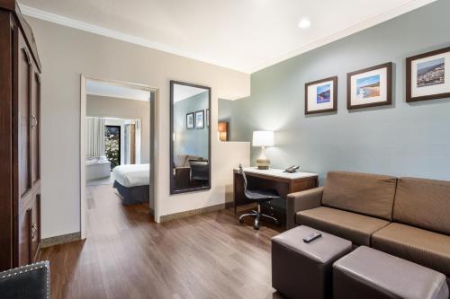 a hotel room with a couch and a desk and a bed at MainStay Suites Orange County John Wayne Airport in Santa Ana