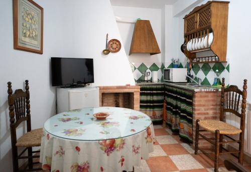 a kitchen with a table and chairs and a tv at APAR. SIERRAGUADALQUIVIR in Quesada