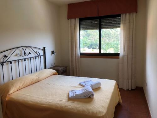 a bedroom with a bed with two towels on it at Apartamentos aDoniña Playa Major Sanxenxo in Sanxenxo