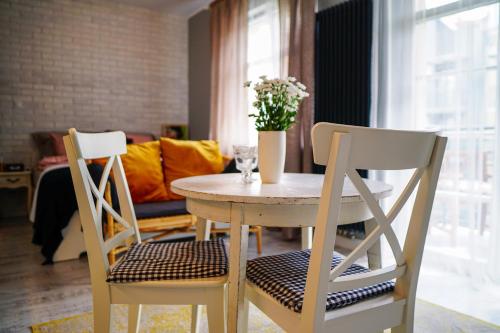 a table and two chairs with a vase of flowers on it at Apartament Ohar Downtown in Elblag