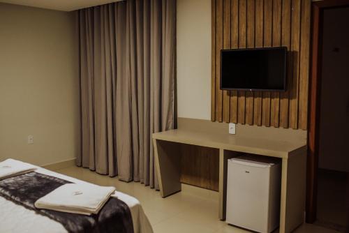 a hotel room with a television on a wall at MANANCIAL HOTEL E EVENTOS in Manhuaçu