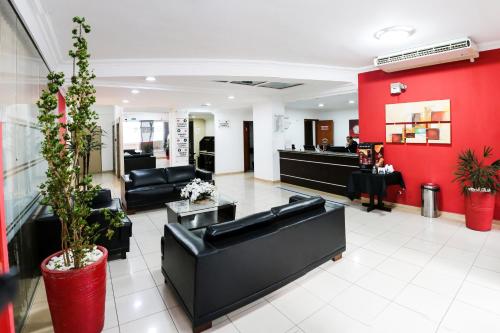 um átrio com mobiliário preto e uma parede vermelha em Polo Hotel em São José dos Campos