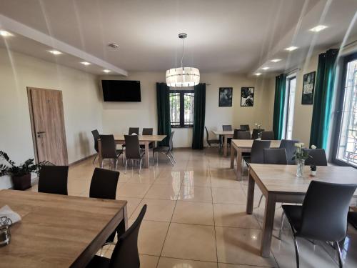 a dining room with tables and chairs and a television at Bar Oaza in Szczerców