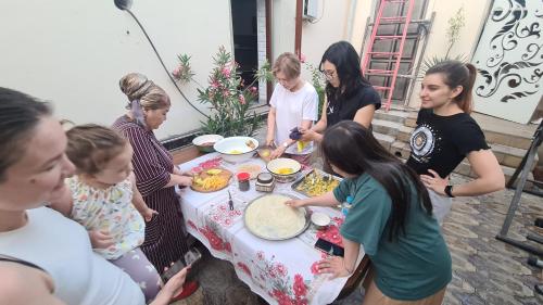 un grupo de personas de pie alrededor de una mesa con comida en Hotel Anor, en Samarkand