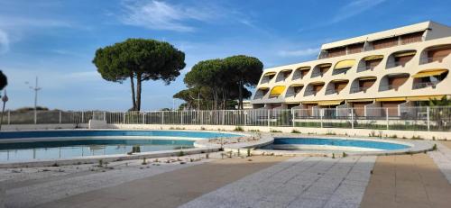 uma piscina em frente a um edifício em Une Escale en bord de Plage avec piscine et jardins em Le Grau-du-Roi