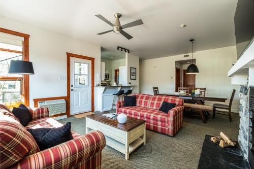 a living room with two couches and a table at Le Serein Condo Tremblant Les-Eaux in Mont-Tremblant