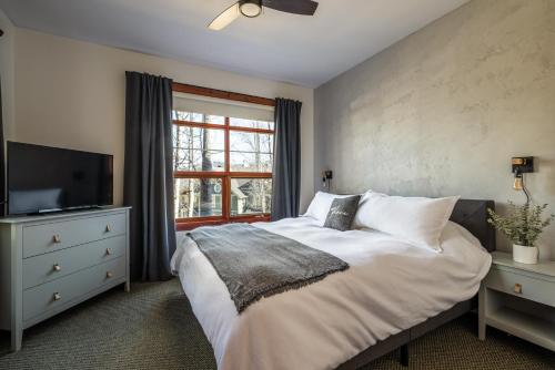 een slaapkamer met een bed, een tv en een raam bij Le Serein Condo 1 chambre à Tremblant Les-Eaux in Mont-Tremblant