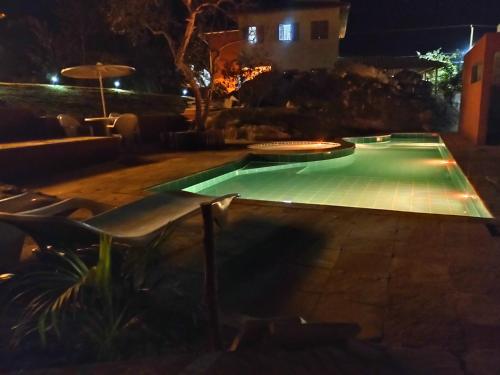 a swimming pool at night with chairs and an umbrella at SO HAM Guest House in Diamantina