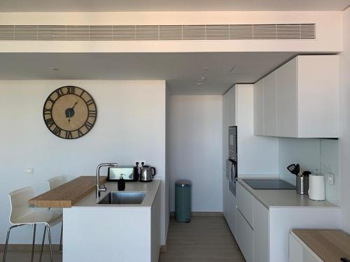 eine Küche mit einem Waschbecken und einer Uhr an der Wand in der Unterkunft Bonito apartamento Carvajal - Fuengirola - The Wave in Fuengirola