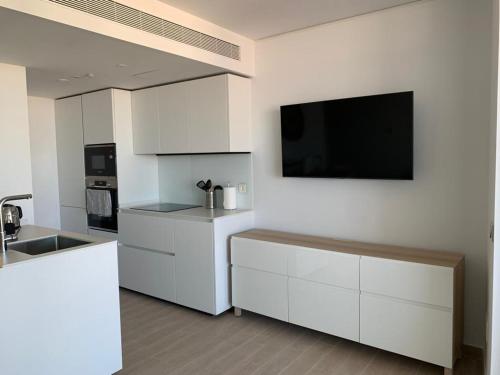 a kitchen with white cabinets and a flat screen tv at Bonito apartamento Carvajal - Fuengirola - The Wave in Fuengirola