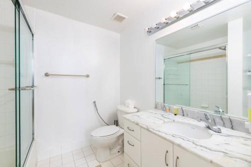 Un baño con inodoro, lavabo y espejo. en 4BR Penthouse with Oceanview at Brickell, Free Parking, en Miami