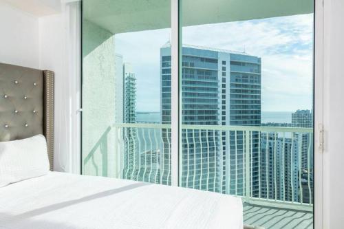 Un dormitorio con una cama blanca y una ventana grande. en 4BR Penthouse with Oceanview at Brickell, Free Parking, en Miami