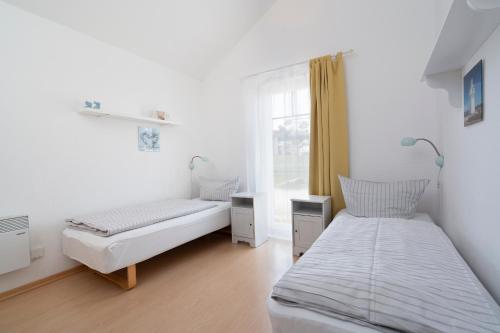 1 dormitorio con 2 camas y ventana en Strandpark Sierksdorf H085, en Sierksdorf