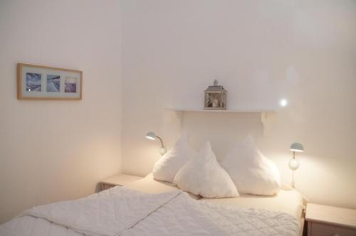 ein Schlafzimmer mit einem weißen Bett mit weißen Kissen in der Unterkunft Strandpark Sierksdorf H090 in Sierksdorf