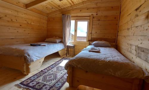 two beds in a log cabin with a window at POKUT HELUN in Rize