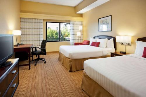 a hotel room with two beds and a desk and a television at Sonesta Select Las Vegas Summerlin in Las Vegas