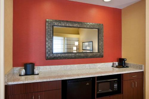 a bathroom with a red wall with a mirror at Sonesta Select Las Vegas Summerlin in Las Vegas
