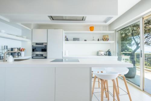 une cuisine avec des comptoirs blancs et une grande fenêtre dans l'établissement  SERRENDY  3 pièces sur les hauteurs de Cannes dans domaine de standing !, à Cannes
