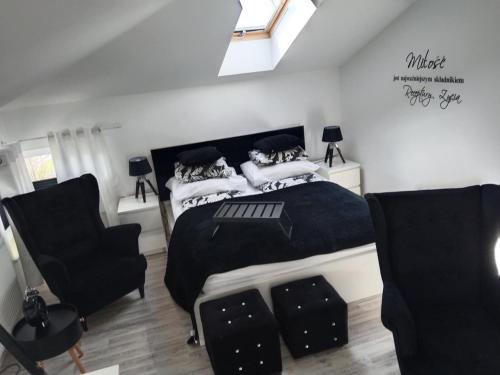a bedroom with a black and white bed and two chairs at Willa La mer in Ustka