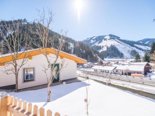 a snow covered building with a fence and mountains in the background at Chalet Windbach in Saalbach Hinterglemm
